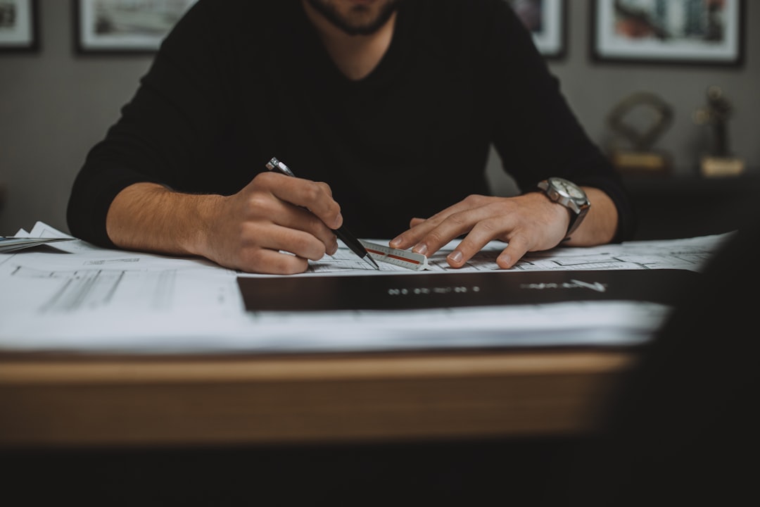 Man working and drawing on blueprints with a pen and ruler.